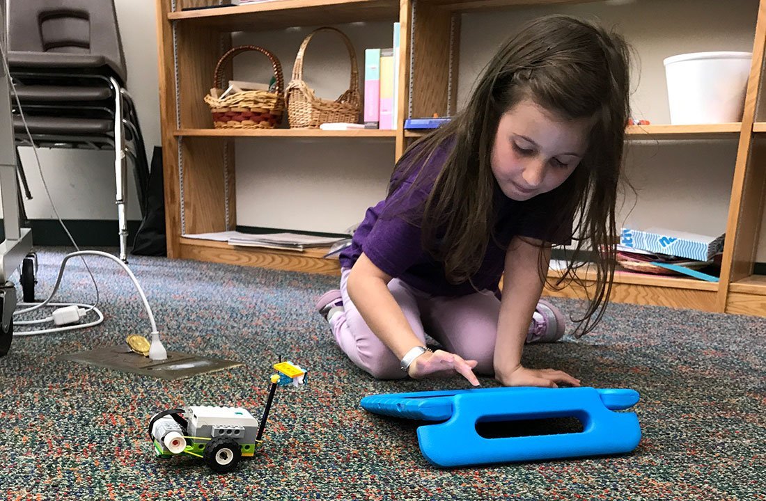 lower school student working on tablet to control robot